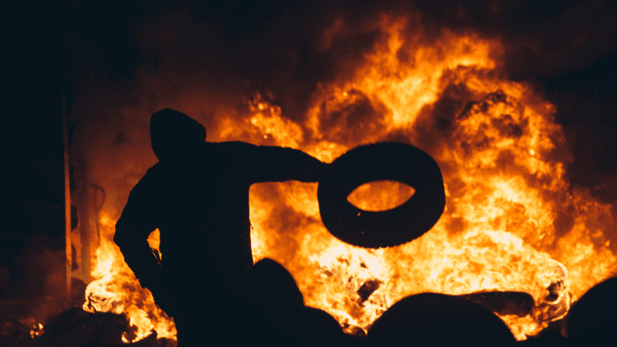 Rioter throwing a tire into a fire